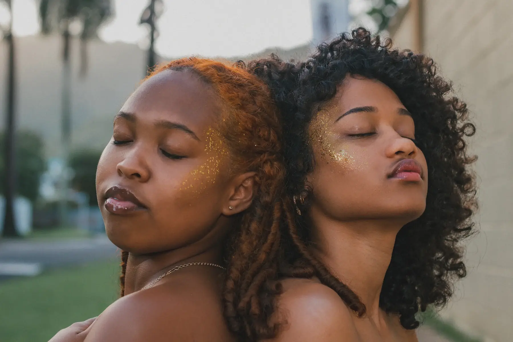 Two women with sun-kissed skin, eyes closed in warm sunlight